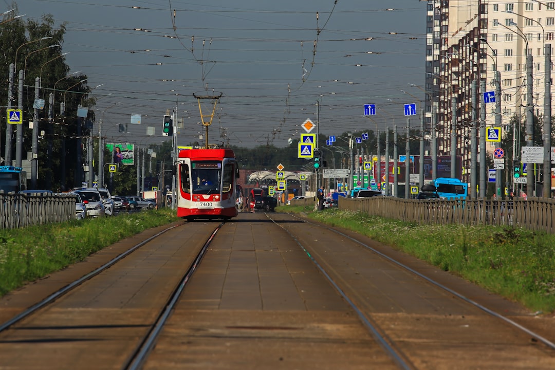 A red train traveling down train tracks next to tall buildings