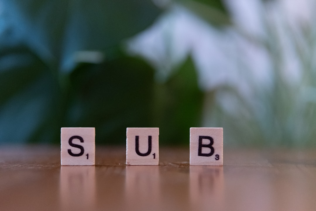 Cubes spelling sub on a table with a plant in the background