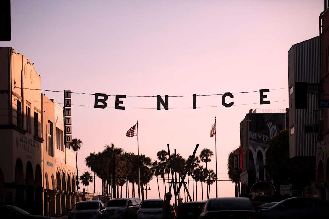 A 'be nice' banner hangs over a street at sunset.
